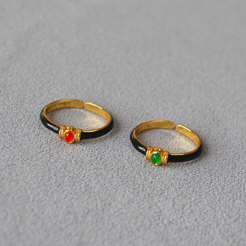 Two gold rings with gemstones on a gray surface