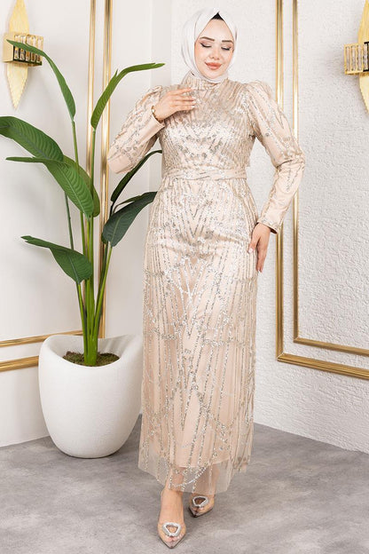 Woman in a sparkly dress standing in a room with a plant and decorative wall.