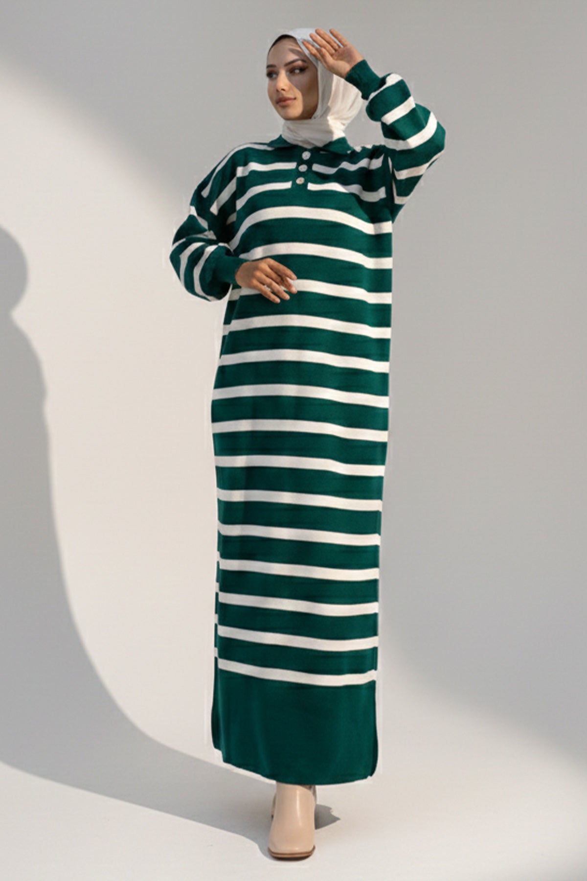 Woman wearing a green and white striped dress against a gray background