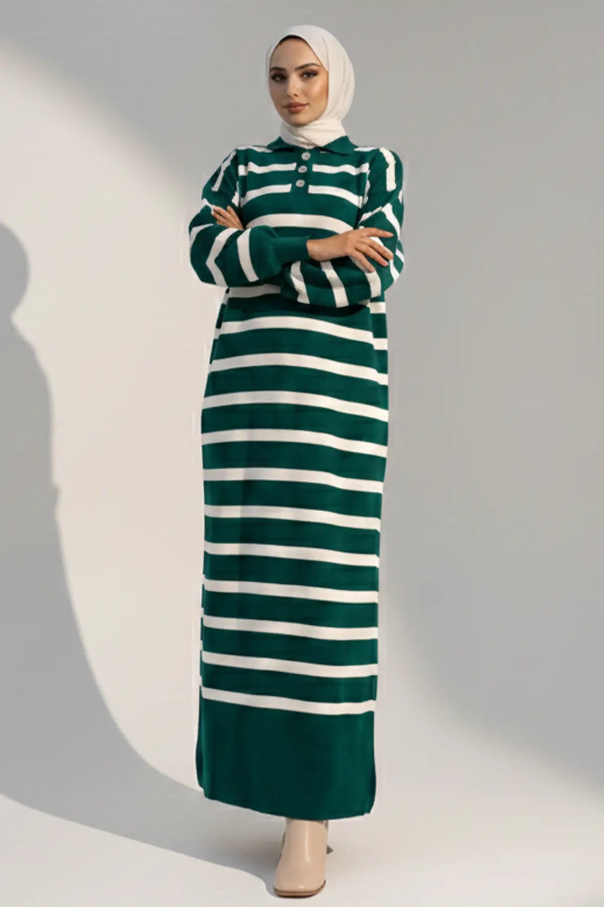 Woman wearing a green and white striped dress against a plain background