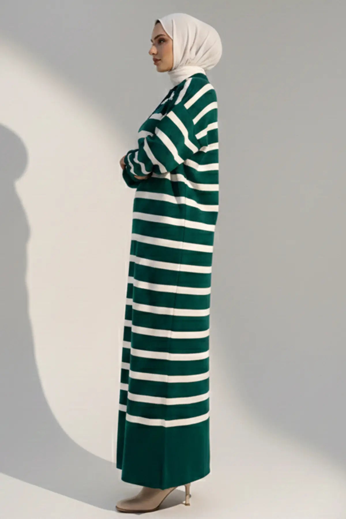Woman wearing a green and white striped dress against a plain background